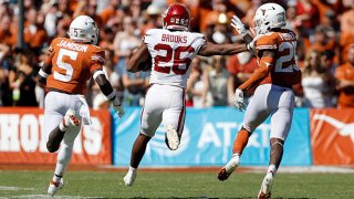 Kennedy Brooks #26 of the Oklahoma Sooners gives a stiff arm to B.J. Foster #25 of the Texas Longhorns in the third quarter during the 2021 AT&T Red River Showdown at Cotton Bowl on Oct. 9, 2021 in Dallas, Texas.