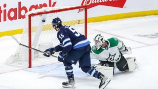 Mark Scheifele #55 of the Winnipeg Jets backhands the puck into the net over goaltender Braden Holtby #70 of the Dallas Stars for the game-winning shootout goal at the Canada Life Centre on Nov. 2, 2021 in Winnipeg, Manitoba, Canada.