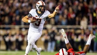 Quarterback Spencer Sanders #3 of the Oklahoma State Cowboys runs past defensive lineman Tyree Wilson #19 of the Texas Tech Red Raiders during the first half of the college football game at Jones AT&T Stadium on Nov. 20, 2021 in Lubbock, Texas.