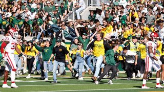 Oklahoma Sooners players walk away as Baylor Bears fans storm the field with time left on the clock in the second half at McLane Stadium on Nov. 13, 2021 in Waco, Texas. Baylor won 27-14.