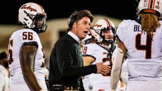 Head coach Mike Gundy of the Oklahoma State Cowboys talks with cornerback Korie Black #4 during the second half of the college football game against the Texas Tech Red Raiders at Jones AT&T Stadium on Nov. 20, 2021 in Lubbock, Texas.