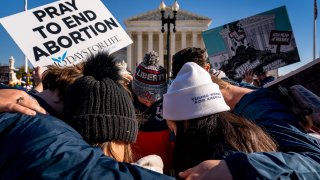 A group of anti-abortion protesters pray together in front of the U.S. Supreme Court