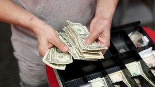 Edwin Lopez sorts the money in the cash register at Frankie’s Pizza on January 12, 2022 in Miami, Florida.