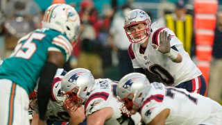 New England Patriots quarterback Mac Jones (10) directs his teammates during the first half of an NFL football game against the Miami Dolphins, Sunday, Jan. 9, 2022, in Miami Gardens, Fla.