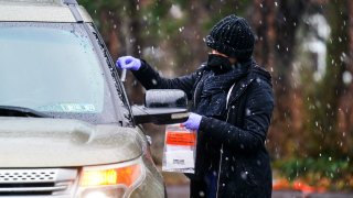 A healthcare worker administers a free drive-thru COVID-19 test at a newly opened site in the parking lot of the Mercy Fitzgerald Hospital in Darby, Pa., Thursday, Jan. 20, 2022.