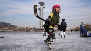 A child practices ice hockey near the Beijing Olympics Tower in Beijing, China, Tuesday, Jan. 18, 2022. The Beijing Winter Olympics is tapping into and encouraging growing interest among Chinese in skiing, skating, hockey and other previously unfamiliar winter sports. It's also creating new business opportunities
