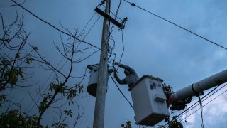 In this July 12, 2018 photo, a laborer from the Puerto Rico Power Authority works to restore power in Adjuntas, Puerto Rico. Puerto Rico's electrical grid is still shaky after Hurricane Irma brushed past the island as a Category 5 storm last Sept. 6 and then Hurricane Maria made a direct hit as a Category 4 storm two weeks later, damaging up to 75 percent of transmission lines.