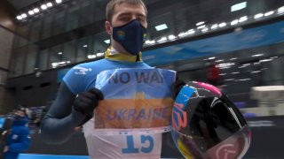 Vladyslav Heraskevych, of Ukraine, holds a sign that reads "No War in Ukraine" after finishing a run at the men's skeleton competition at the 2022 Winter Olympics