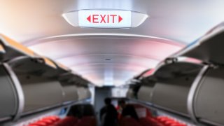 Emergency exit sign on ceiling inside passenger aircraft cabin