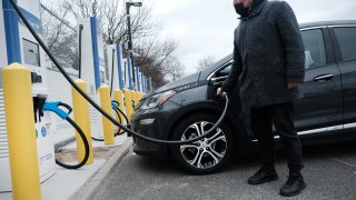 A driver uses a fast-charging station for electric in the cell phone lot at John F. Kennedy (JFK) airport on April 2, 2021 in New York City.