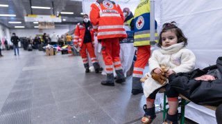 A little girl and a baby wait next to the Red Cross station with mother (not pictured) as people fleeing Ukraine arrive on a train from Poland at Hauptbahnhof main railway station on March 4, 2022 in Berlin, Germany. Hundreds of thousands of people, mainly Ukrainian women and children as well as foreigners living or working in Ukraine, have fled the country as the current Russian military invasion continues to inflict growing casualties on the civilian population.
