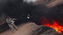 A soldier tosses unserviceable uniforms into a burn pit in Iraq on March 10, 2008.
