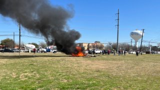 A helicopter burns after crashing into a vacant lot in Rowlett, Texas, March, 25, 2022.