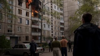 People watch as a residential building burns following a Russian bombardment in Kharkiv, Ukraine, Monday, April 25, 2022.