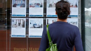 A customer looks at listings on display outside a Brown Harris Stevens offices in New York.