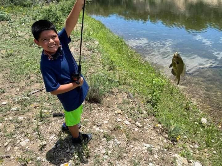 Jose Flores holding a fishing rod with a fish on the line.