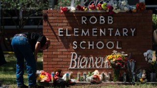 A law enforcement personnel lights a candle outside Robb Elementary School in Uvalde, Texas, Wednesday, May 25, 2022.