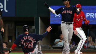 J.D. Martinez #28 slides home after Rafael Devers #11 of the Boston Red Sox scored against the Texas Rangers in the seventh inning at Globe Life Field on May 13, 2022 in Arlington, Texas.