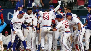 Adolis Garcia #53 of the Texas Rangers is greeted by his teammates as he crosses home plate after a walkoff solo home run in the ninth inning against the Washington Nationals at Globe Life Field on June 25, 2022 in Arlington, Texas.