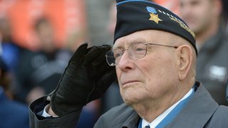 File - Medal of Honor Recipient Hershel "Woody" Williams salutes during the playing of the National Anthem prior to the Military Bowl on Dec. 27, 2012, in Washington, DC
