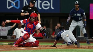 Sam Haggerty #0 of the Seattle Mariners dives home to score on an inside the park home run as Jonah Heim #28 of the Texas Rangers misses the throw at Globe Life Field on July 14, 2022 in Arlington, Texas.