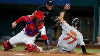 Terrin Vavra #77 of the Baltimore Orioles scores a run as Jonah Heim #28 of the Texas Rangers applies the tag late in the second inning at Globe Life Field on August 01, 2022 in Arlington, Texas.