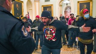 FILE – In this Jan. 6, 2021, photo, Trump supporters, including Douglas Jensen, center, confront U.S. Capitol Police in the hallway outside of the Senate chamber at the Capitol in Washington.