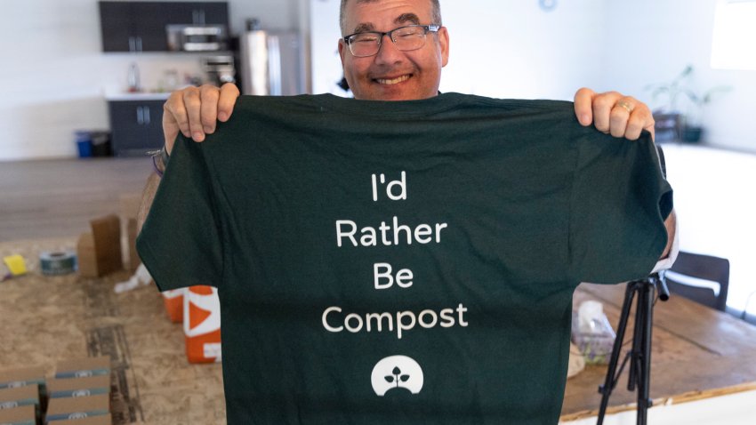Return Home CEO Micah Truman holds up a t-shirt with a light-hearted slogan, reading “I’d rather be compost”, during a tour of the Return Home funeral home which specializes in human composting in Auburn, Washington on March 14, 2022. – Washington in 2019 became the first in the United States to make it a legal alternative to cremation. (Photo by Jason Redmond / AFP) (Photo by JASON REDMOND/AFP via Getty Images)