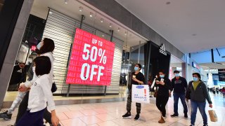 People walk stores offering sales at a shopping mall in Santa Anita, California on December 20, 2021.