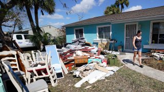 Christina Barrett walks among the water damaged furniture outside her home