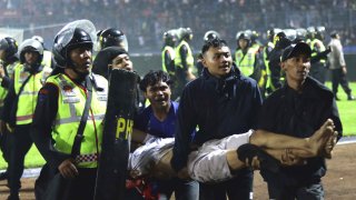 Soccer fans carry an injured man following clashes during a soccer match at Kanjuruhan Stadium in Malang, East Java, Indonesia, Saturday, Oct. 1, 2022.