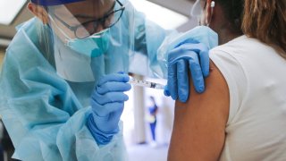 A nurse administers a flu vaccination shot to a woman at a free clinic held at a local library on October 14, 2020 in Lakewood, California.