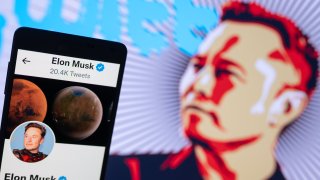 Elon Musk’s Twitter account displayed on a mobile with Elon Musk in the background are seen in this illustration. In Brussels – Belgium on 19 November 2022.