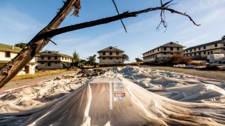 FILE – Labeled with asbestos and lead warnings, sheeting covers rubble from demolished barracks at Fort Ord on Thursday, April 29, 2021, in Fort Ord, Calif.