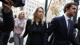 Former Theranos CEO Elizabeth Holmes (C) arrives at federal court with her partner Billy Evans (R) and mother Noel Holmes on November 18, 2022 in San Jose, California.