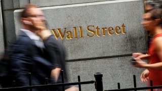 People walk on Wall St. outside the New York Stock Exchange, August 7, 2019.