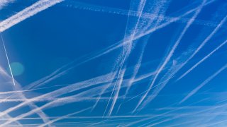 WASSENAAR, NETHERLANDS – AUGUST 08: Condensation trails created by jet engines of countless airplanes are seen in the early morning on August 8, 2022 in Wassenaar, Netherlands. Jet engines produce humid hot air and water vapour as a bi-product of burning fuel that condensates and crystallizes into ice high up in the freezing sky. These white lines are these condensation trails and are also called contrails.