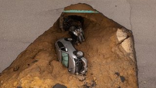 A car and a pickup truck are seen inside a sinkhole.