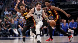 Luka Doncic #77 of the Dallas Mavericks dribbles the ball against Trae Young #11 of the Atlanta Hawks and De'Andre Hunter #12 of the Atlanta Hawks in the first quart at American Airlines Center on January 18, 2023 in Dallas, Texas.