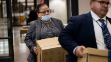 Dallas Police detectives Christine Ramirez (left) and Jose Ortiz Vives carry in boxes of case files from Dallas Police Department’s investigation into the killing of Marisela Botello Valadez during a hearing inside the 282nd District Court at the Frank Crowley Courts Building in Dallas on Monday.