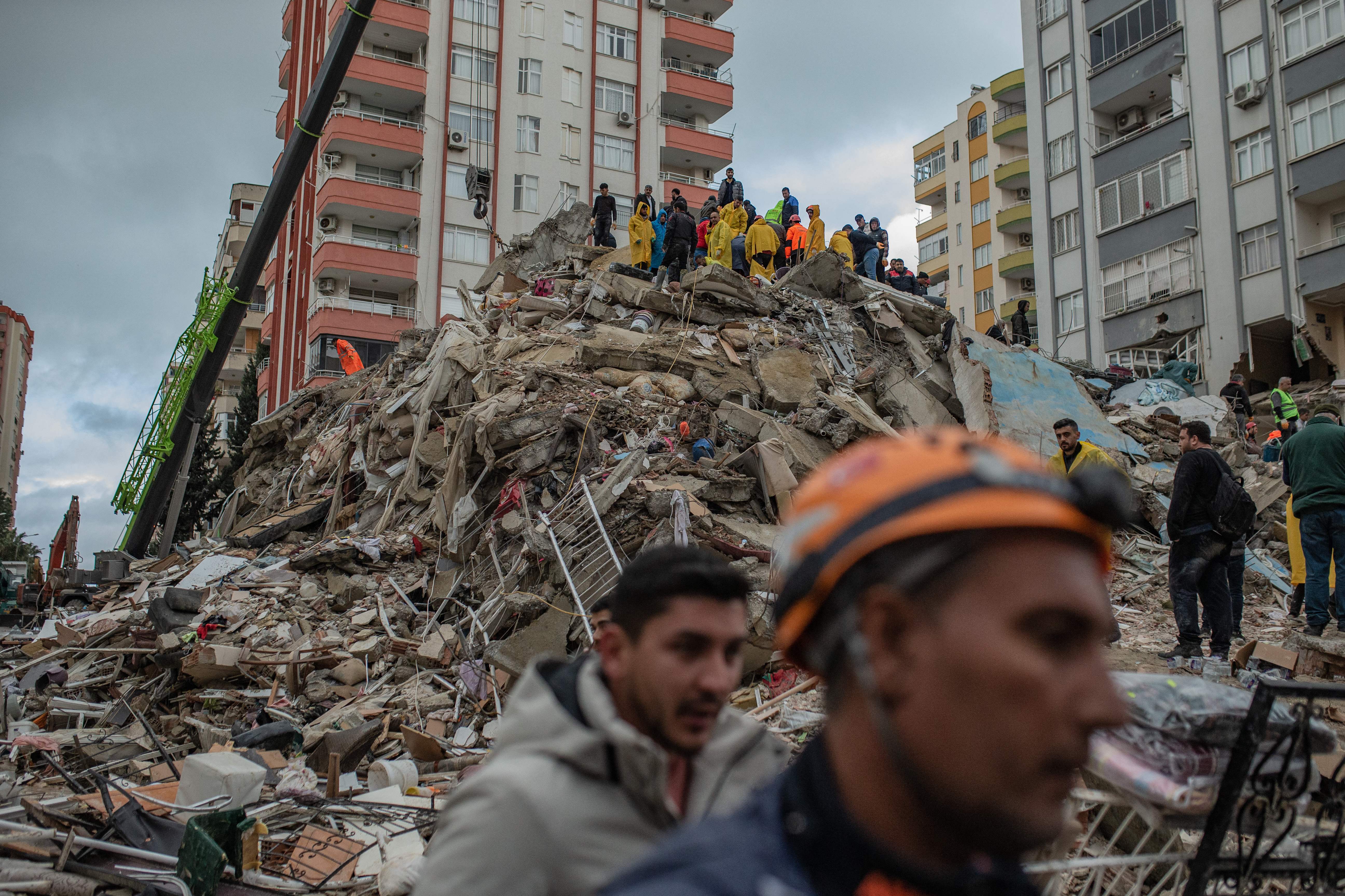 Rescuers search for victims and survivors amidst the rubble of a building that collapsed in Adana, Turkey, Feb. 6, 2023, after a 7.8-magnitude earthquake struck the country’s southeastern border with Syria.