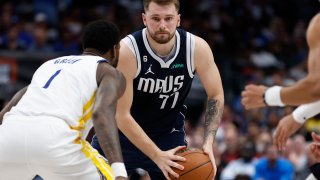 Luka Doncic #77 of the Dallas Mavericks looks to pass while defended by JaMychal Green #1 of the Golden State Warriors in the second half at American Airlines Center on March 22, 2023 in Dallas, Texas.