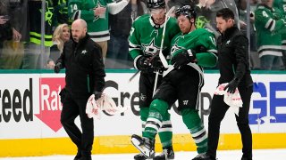 Dallas Stars' Joe Pavelski, second from right, is helped off the ice by Mason Marchment and staff after suffering an unknown injury in the second period of Game 1 of an NHL hockey Stanley Cup first-round playoff series against the Minnesota Wild, Monday, April 17, 2023, in Dallas.