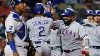 Texas Rangers' Marcus Semien (2) is congratulated by Sandy Leon, right, after hitting a three-run home run as Kansas City Royals catcher Salvador Perez, left, stands at home plate during the sixth inning of a baseball game in Kansas City, Mo., Tuesday, April 18, 2023.