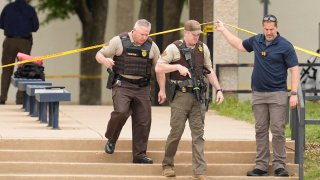 Oklahoma state troopers walk under police tape following a fatal shooting at Rose State College in Midwest City, Okla., on Monday, April 24, 2023.
