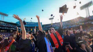 Northeastern University students celebrate the conclusion of their University’s 121st undergraduate commencement at Fenway Park by throwing their caps in the air.