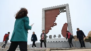 Chinese tourists walk past an installation depicting Taiwan (R) and mainland China at a tourist area on Pingtan island, the closest point to Taiwan, in China’s southeast Fujian province on April 6, 2023.