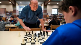 Custodian and chess coach David Bishop challenges 6th-grader Owen Isenhour during after-school practice, Tuesday, April 25, 2023, in Hampden, Maine. Under Bishop’s tutelage, the Reeds Brook Middle School chess team has gained national recognition. (AP Photo/Robert F. Bukaty)