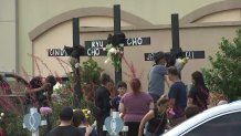 An artist paints on crosses the names of eight victims killed Saturday, May 6, 2023, in a mass shooting at the Allen Premium Outlets in Allen, Texas, photo taken Monday, May 8, 2023.