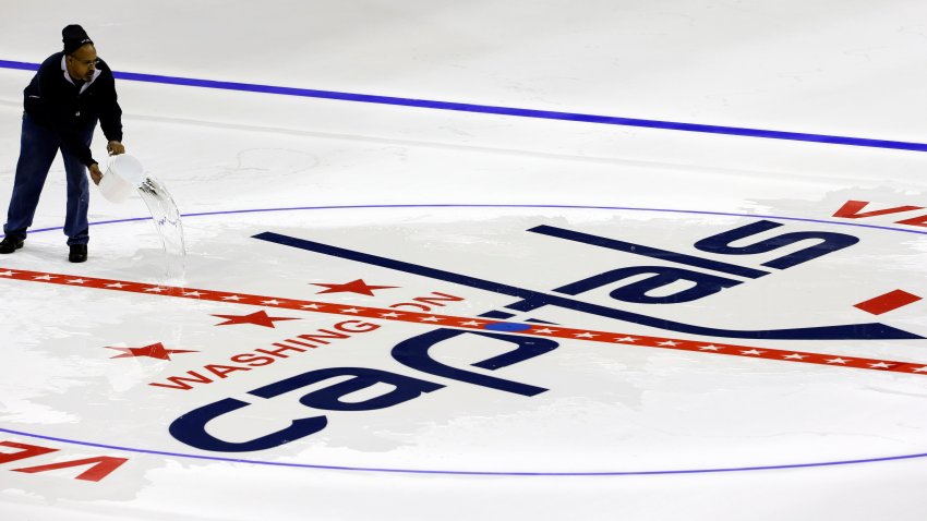 Philip Westmoreland throws water on the Washington Capitals logo at center ice as the logos are placed and the lines painted in preparation for the upcoming NHL hockey season at Verizon Center, Wednesday, Jan. 9, 2013, in Washington. (AP Photo/Alex Brandon)